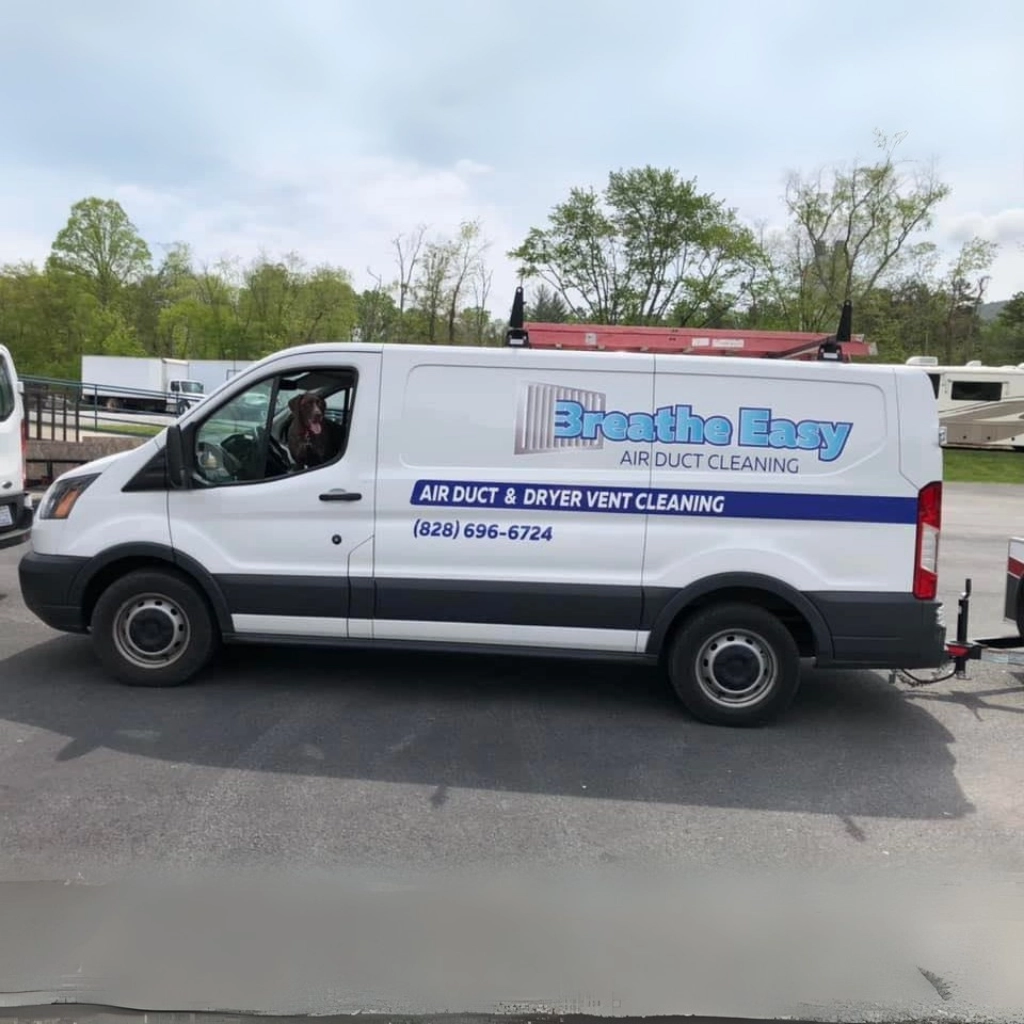 Breathe Easy Air Duct Cleaning service van parked outdoors with a dog sitting in the driver’s seat, showcasing the company logo and contact information on the side.