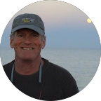 Bo Williams smiling and standing in front of a body of water in the background